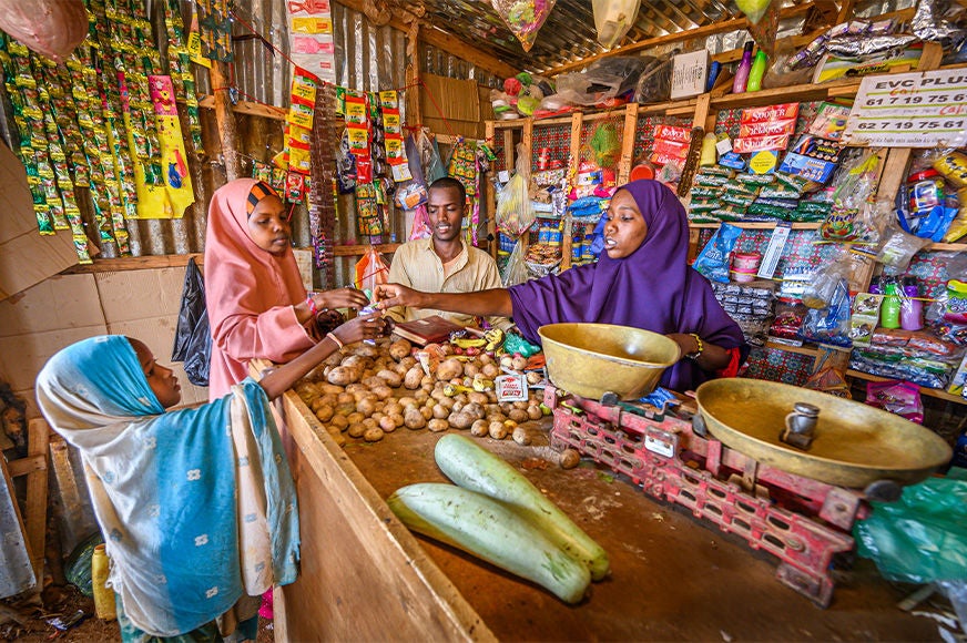 Mariam (right) and Ali (left) serve customers in the store they manage on behalf of the savings program supported by World Vision. (Somalia, 2023)