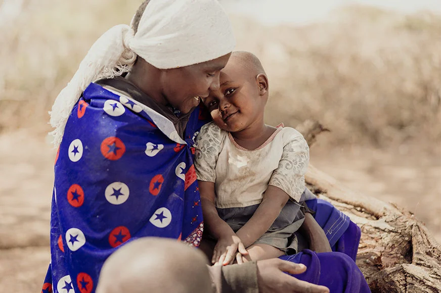 Lea holds her daughter Narukoki with love and hope. Child sponsorship has brought new light into their lives. (Tanzania, 2024) 