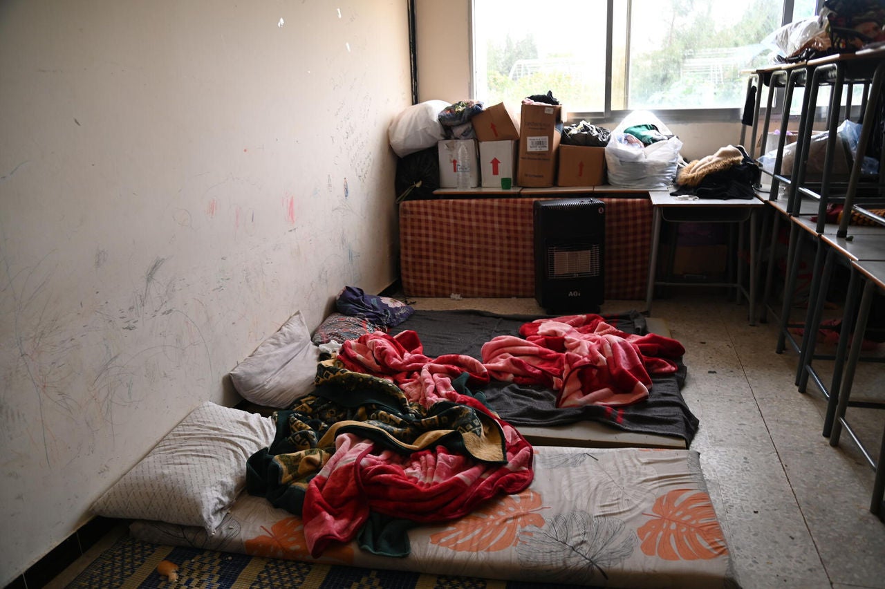 Bedding lies rumpled on thin mattresses on a hard floor. 