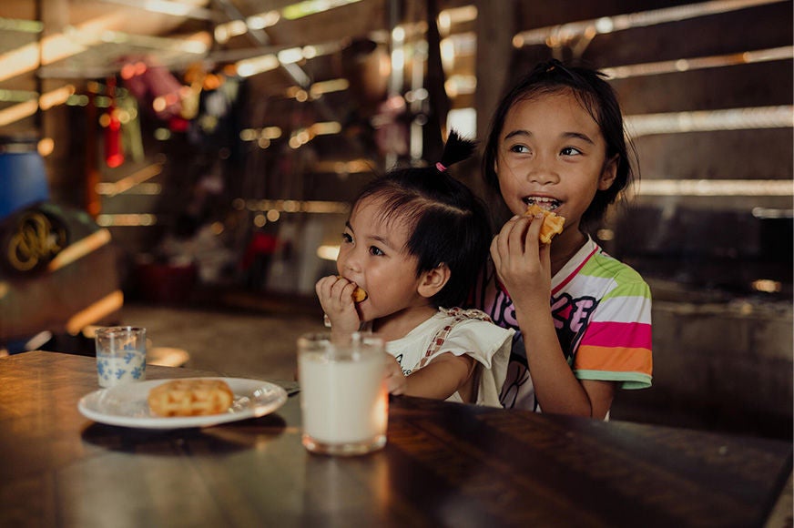 Two girls sitting at the table in their house and enjoying a meal together.