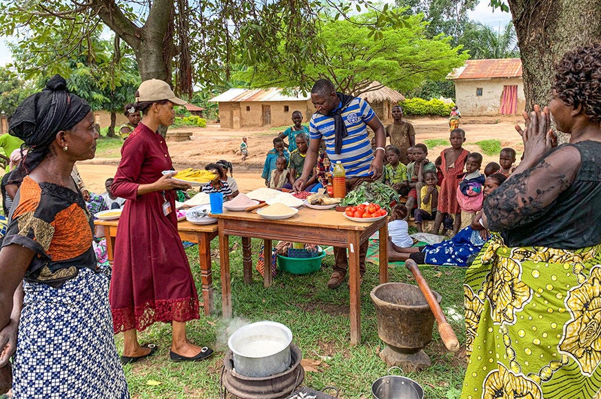 People gathered outside for a training session on malnutrition prevention, which included a cooking demonstration.