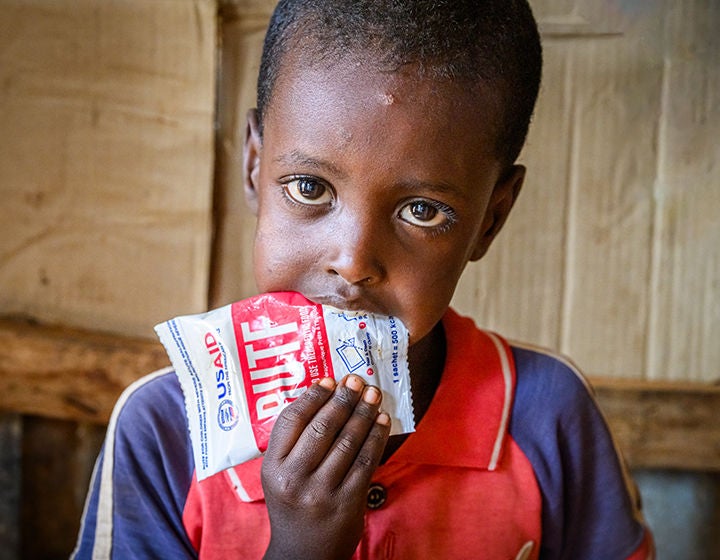 A young boy eating from an emergency food packet.