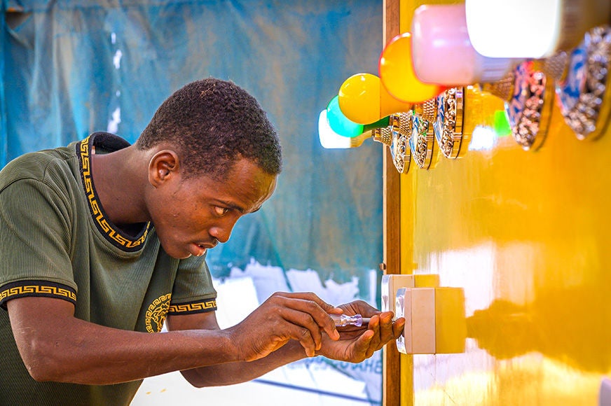 A man practices installing switches on a panel of lights during class at a World Vision Technical Vocational and Education center. (Somalia, 2023)