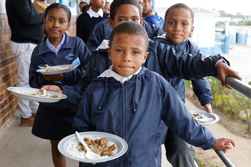 A group of students are holding a plate as they prepare to eat lunch in school.