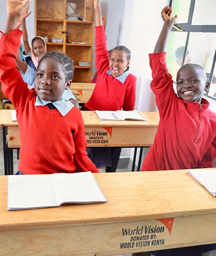 Students raise their hands in a classroom.