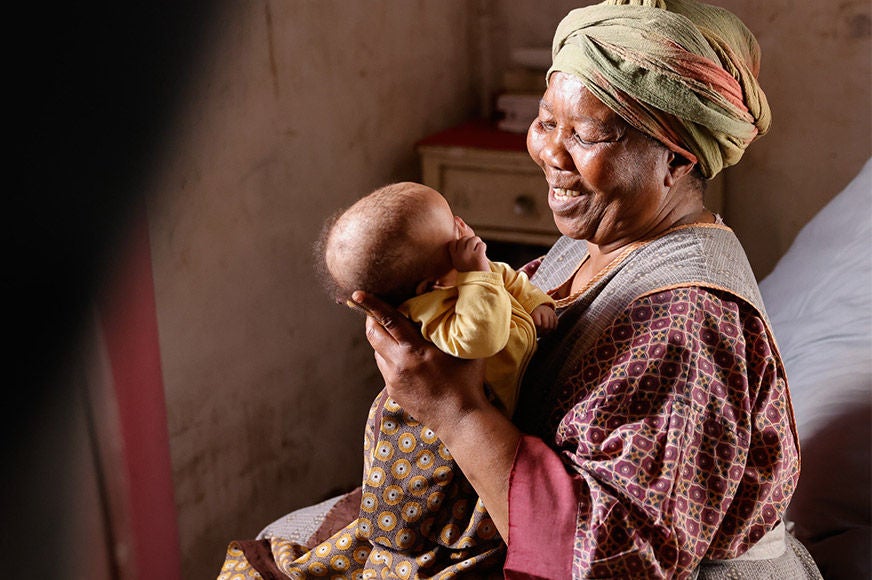 A woman is smiling while gently holding a baby.