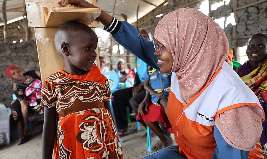 A World Vision health worker measures the height of a young girl as part of a nutrition project in partnership with UNICEF. (Kenya, 2023)