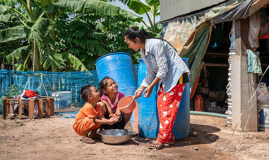 15-year-old sponsored child, Nita (right), helps her siblings wash their hands and practice good hygiene. (Cambodia, 2023)