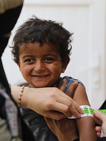  A physician places a mid-upper arm circumference tape measure on a young boy’s arm to see if he has recovered from malnutrition. (Syria, 2023).