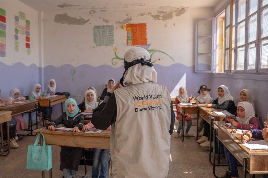 Caption: World Vision staff distributes backpacks and school kits to children affected by the Syria earthquake. (Syria, 2023) .