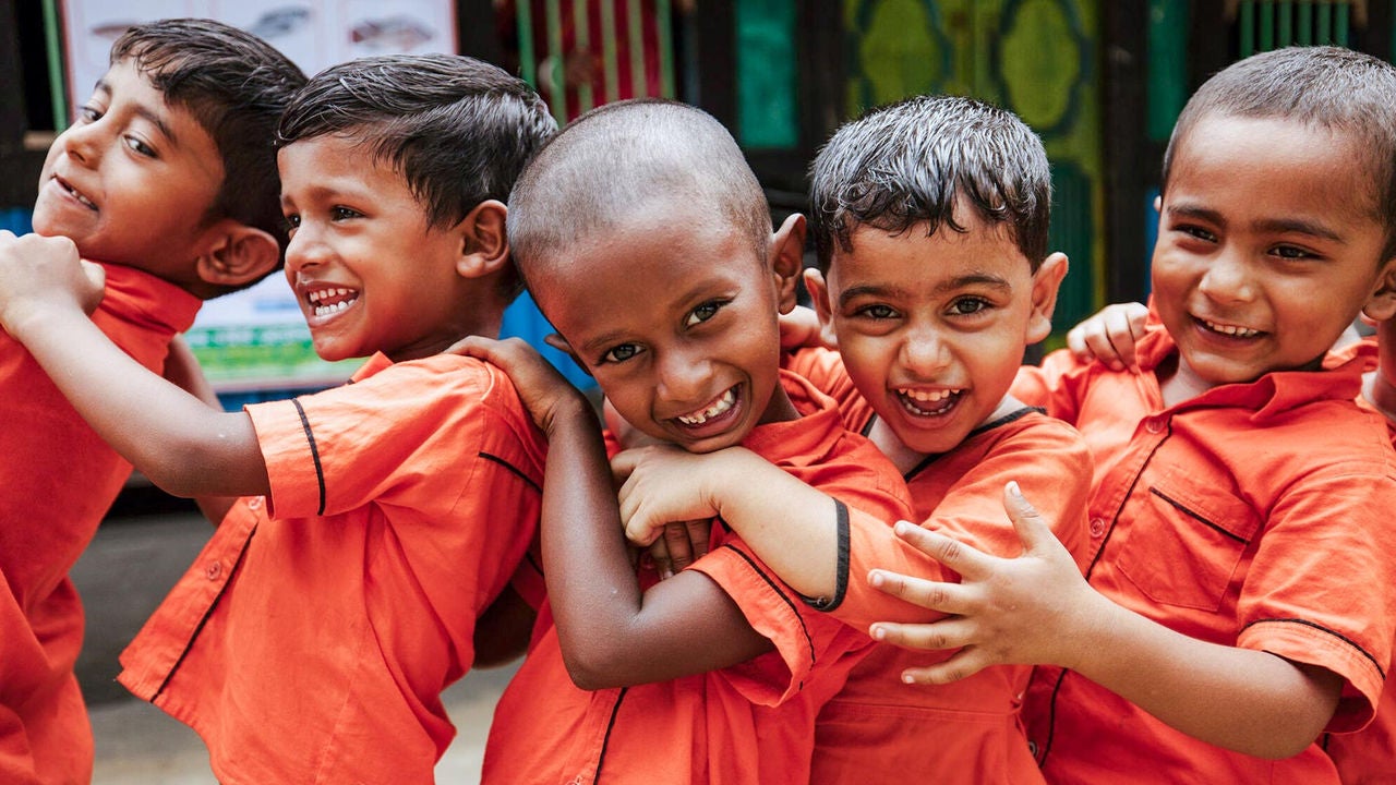 Small kids wearing an orange uniform are lined up during playtime in a Learning Roots Program. (Bangladesh, 2023).