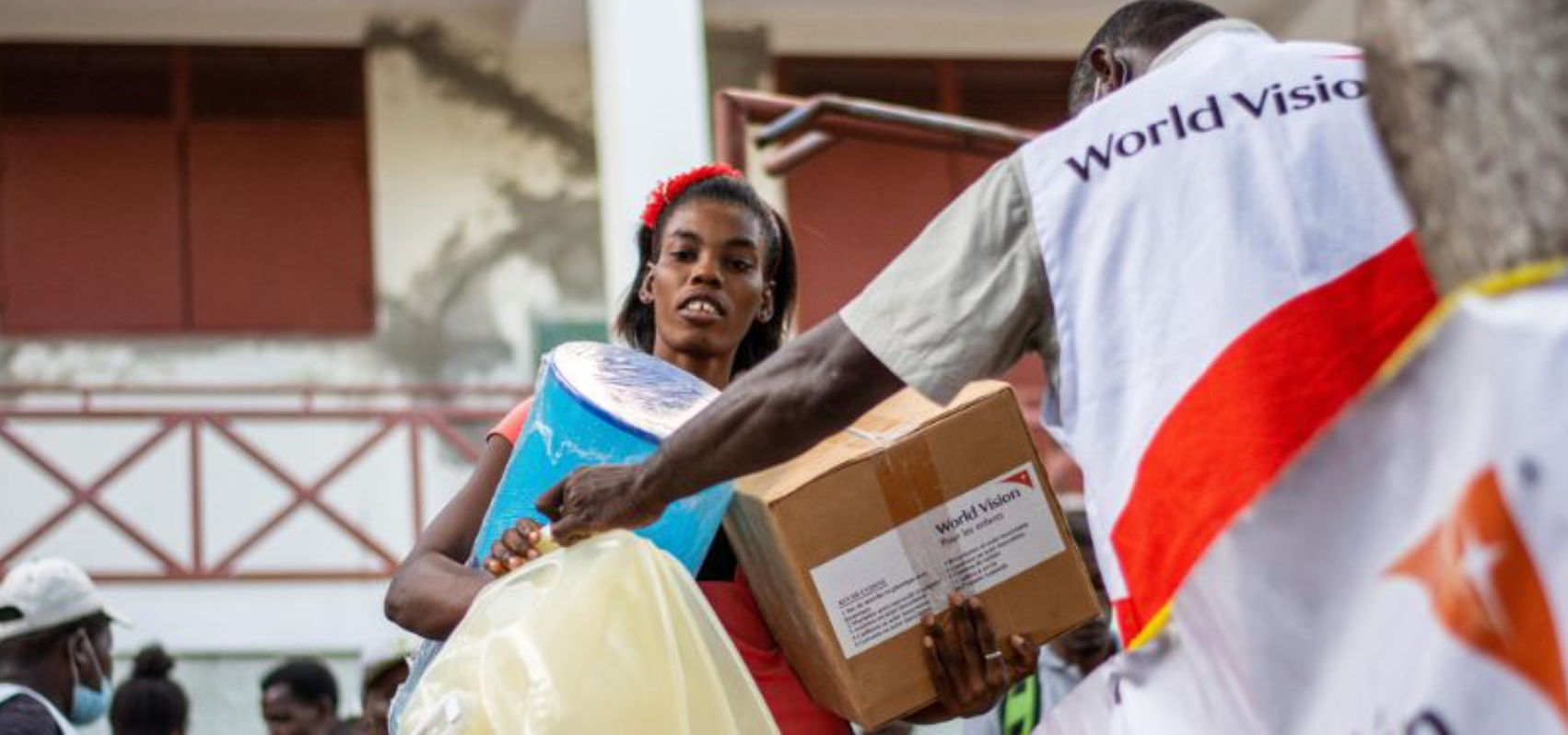A woman carrying relief supplies given to her by a World Vision staff member