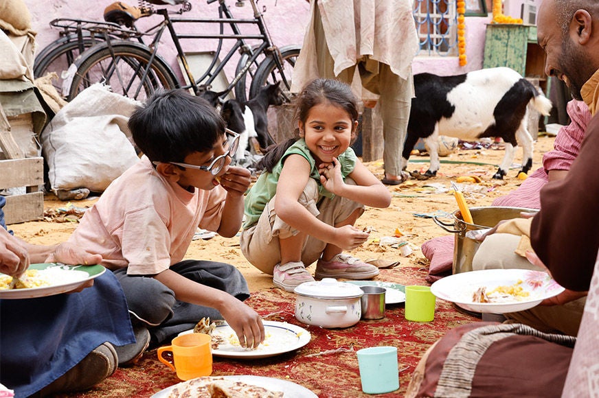 A boy and a girl are enjoying their meal with their family.