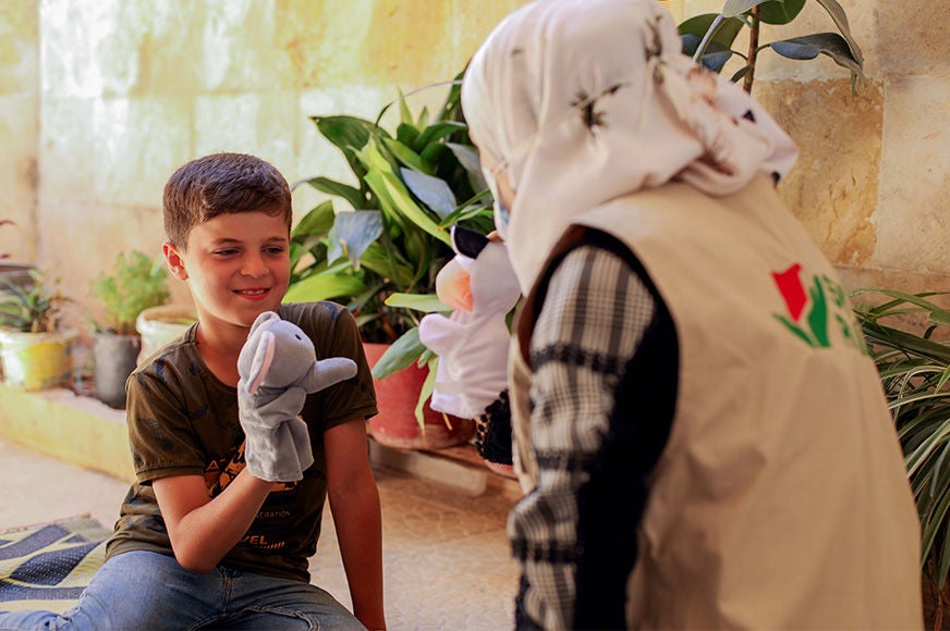 A boy plays with puppets during a psychological support session with a World Vision partner staff member. (Syria, 2023).