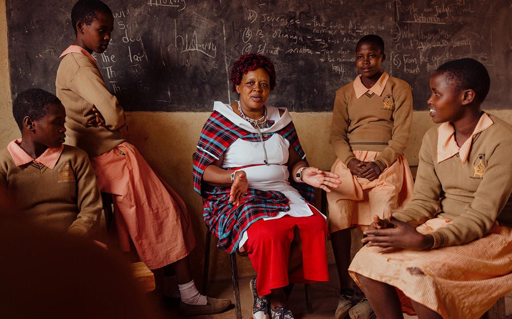 Peninah, an advocate for girls in her community, is sitting in a classroom with her students. 