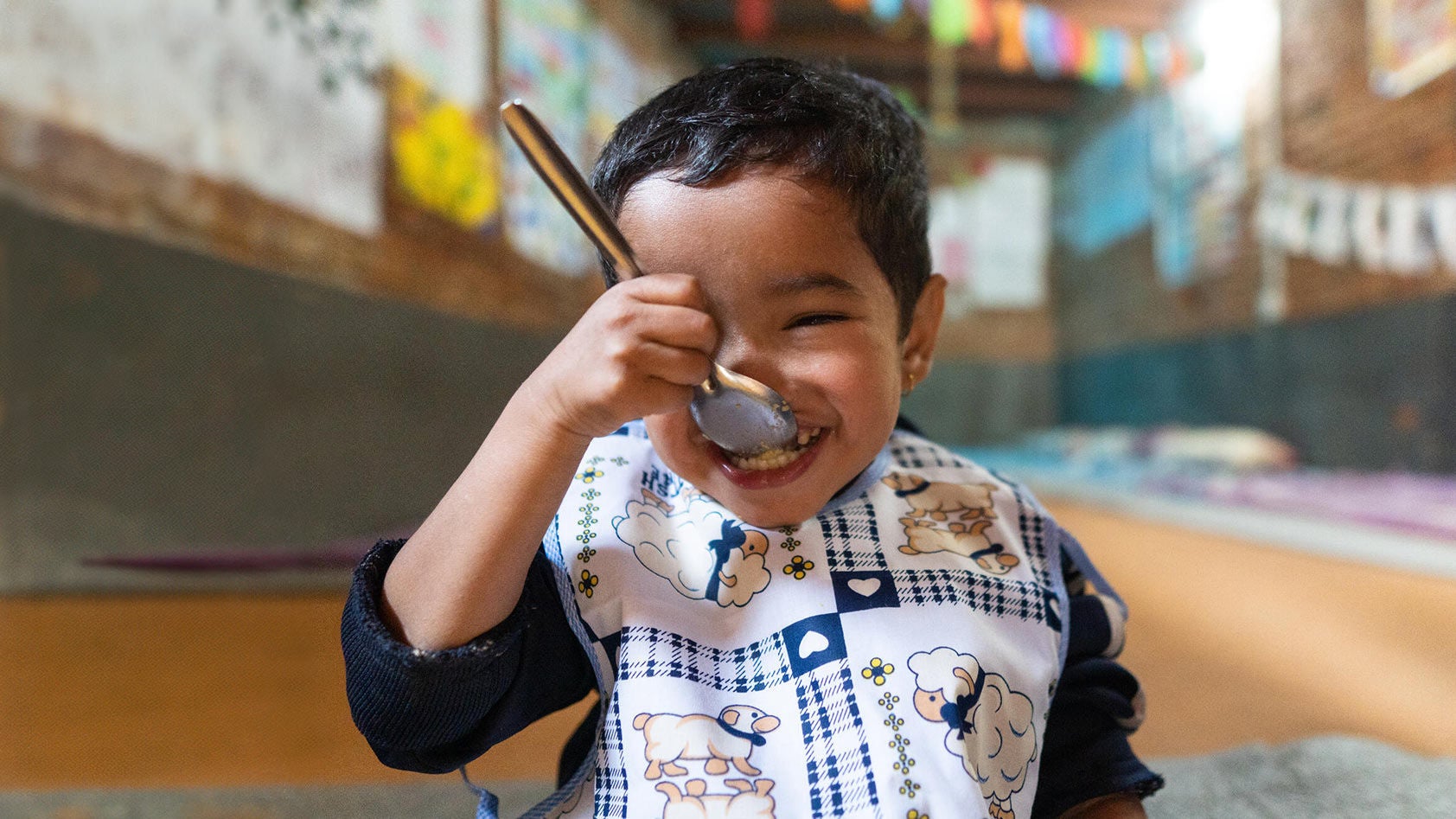 A young boy is enjoying his food as he eats in a classroom. (Nepal, 2023)