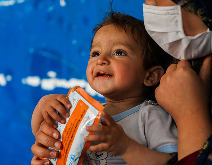 A child is enjoying eating a ready-to-use therapeutic food packet.