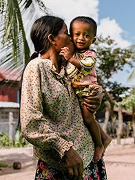 A woman standing outdoors carrying a child.