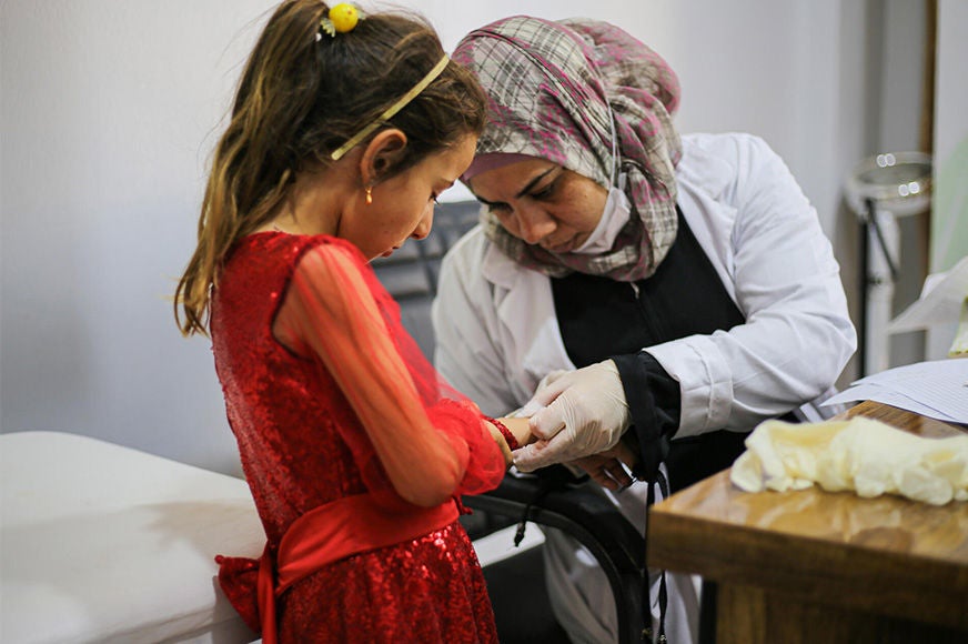 A child is receiving treatment from a World Vision healthcare staff.  (Syria, 2023)