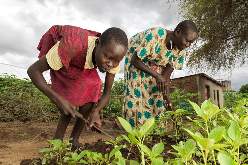 A woman, a member of the World Vision support group, and her daughter are attending to plants in the garden. (South Sudan, 2022)