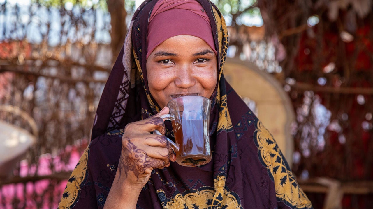 Habiba, a teenage girl from Somalia, is drinking a cup of tea outside her home. (Somalia, 2023).