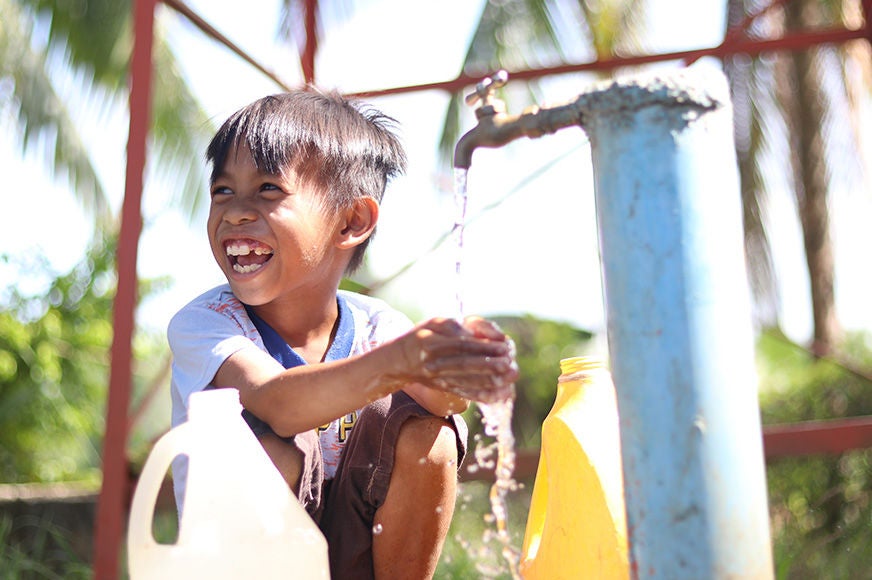 Jory laughs as he washes his hands from an outdoor faucet. (Philippines, 2020)