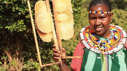 A girl holds honeycombs that were harvested from her family’s beehives. (Kenya, 2023).