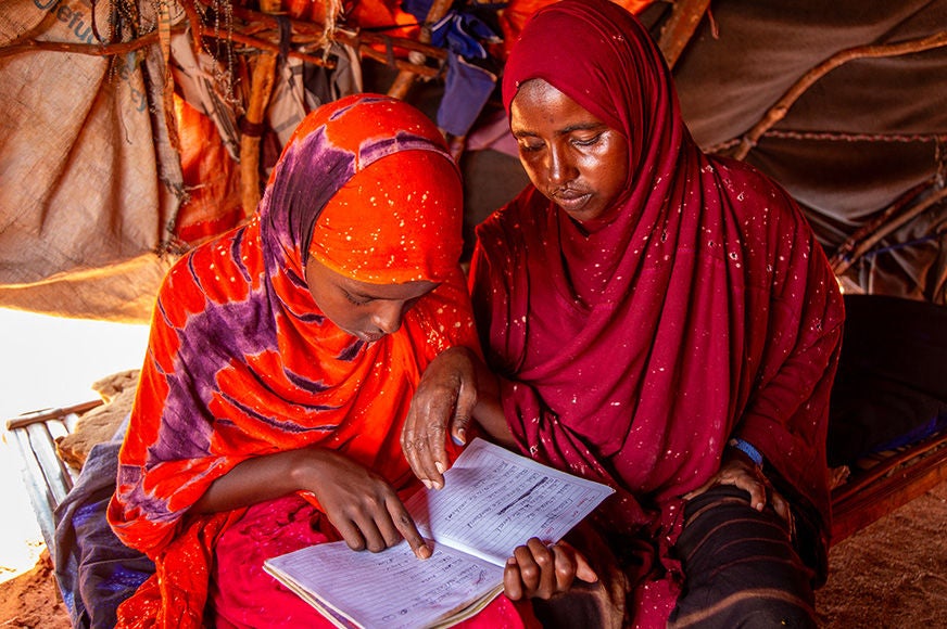 Nour sits with her daughter as she practices reading in Dollow, Somalia.